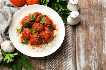 Tasty meatballs with sauce, rice and products on wooden table, flat lay. Space for text