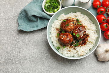 Delicious rice with meatballs, sauce and green onions on grey table, flat lay. Space for text