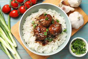 Delicious rice with meatballs, sauce and green onions on blue wooden table, flat lay