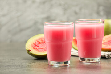 Refreshing guava juice and fresh fruits on grey table, closeup