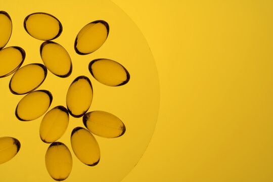 Colorful Omega-3 and Vitamin D capsules on a yellow background