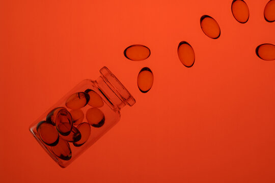 Colorful omega-3 and vitamin D capsules spilled from a jar