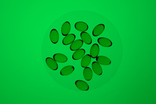 Omega-3 and vitamin D capsules on a vibrant green background