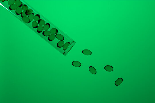 Omega-3 and Vitamin D capsules on green background
