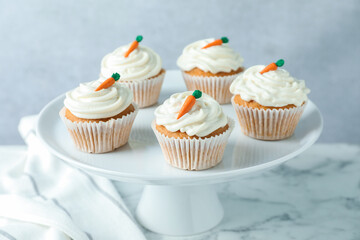 Delicious carrot cupcakes on white marble table against grey background, closeup