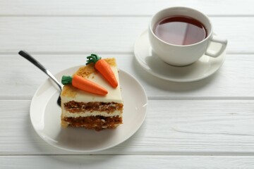 Piece of delicious homemade carrot cake with tea on white wooden table