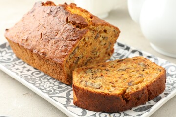 Cut homemade carrot cake with nuts on light grey table, closeup