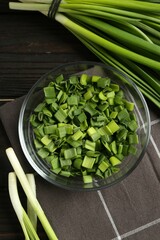 Whole and cut fresh green onions on wooden table, flat lay