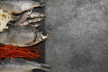 Many different dried fish snacks on grey table, top view. Space for text