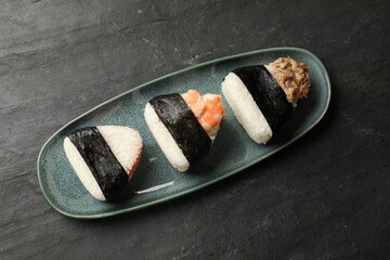 Tasty onigiri (Japanese rice balls) served on black table, top view
