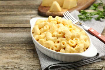 Delicious pasta with cheese sauce, parsley and fork on wooden table, closeup