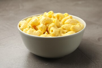 Delicious pasta with cheese sauce in bowl on grey table, closeup