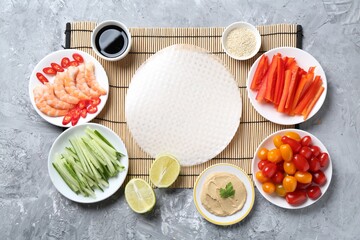 Rice paper sheets and different ingredients on light grey table, flat lay