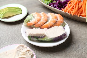 Rice paper sheets and different ingredients on grey wooden table, closeup