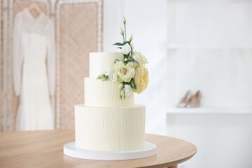Delicious wedding cake with floral decor on wooden table indoors