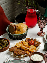 Big cutlets and roasted potatoes in plate, compote, dolma, yogurt
