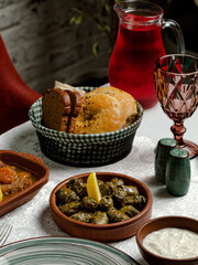 Grape dolma in ceramic pot, bread, empty glass