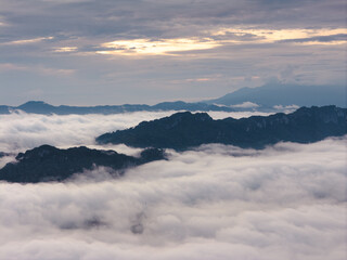 An wide Aerial view of a mountainous landscape with green fields and a village in the foreground. The mountain dominates the background, partially covered by clouds. Tana Toraja - Indonesia 