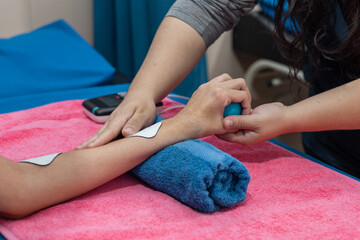 Therapist helps a patient using electro pads and grip ball for guided hand rehabilitation.   © Alejandro