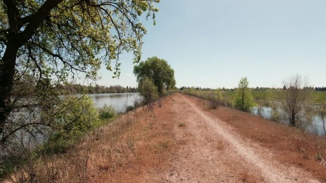 Walking on levee next to a river and oak trees 