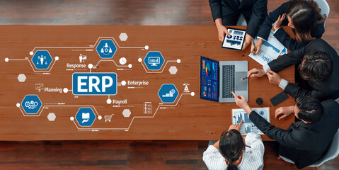 A diverse team collaborates in a modern office discussing ERP solutions, analyzing data and strategies with technology tools, fostering innovation and productivity. Amity