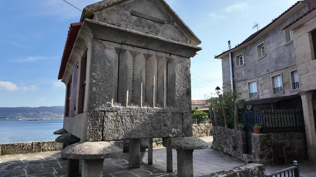 Traditional galician granaries, known as horreos, stand on stilts by the water's edge, topped with stone crosses in combarro, spain
