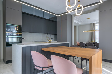 The interior of the kitchen in a modern apartment. Stylish furniture with built-in appliances, elegant lamps.