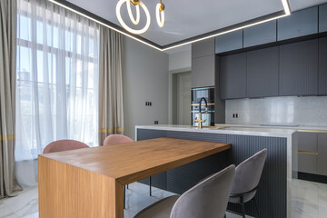 An elegant kitchen with modern built-in appliances, stylish fixtures and a large window with transparent curtains.