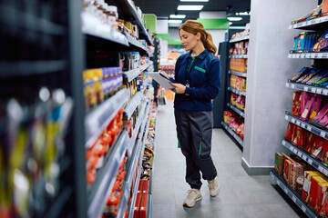 Supermarket manager checking stock of products while working at store.