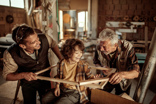 Three generations of men bonding in woodworking workshop