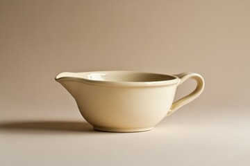 A cream colored ceramic gravy boat with a handle