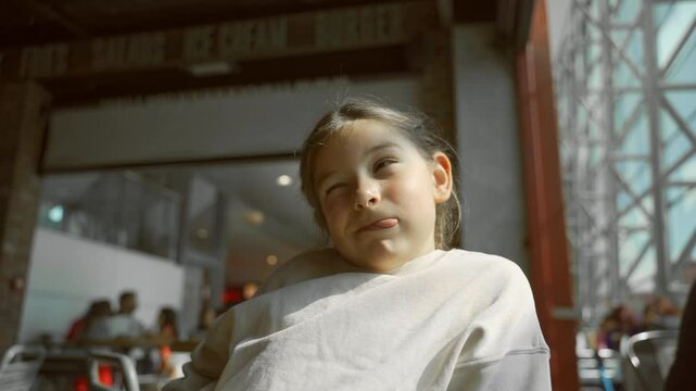 Relaxed young girl enjoying a sunlit outdoor cafe setting, smking face