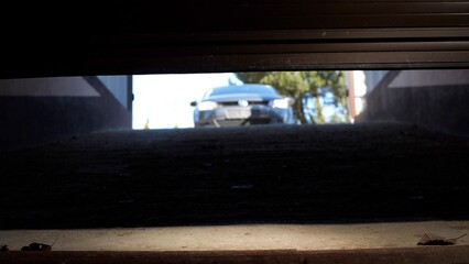 Car is entering a garage with the door open, viewed from inside the garage. The car is approaching...