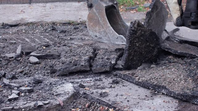 Heavy machinery is actively excavating and removing broken asphalt and concrete for vital and crucial repair work