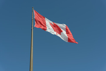 the flag of Canada fluttering in the wind on a blue sky