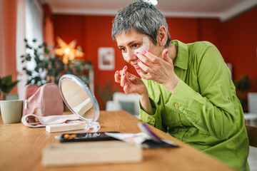 Mature woman put eyes patches have beauty aging treatment at home
