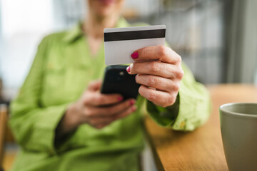 close up on woman hands hold cellphone and credit card for shopping