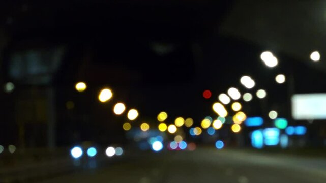 Night city lights view from a moving car on a night road, urban traffic at dusk