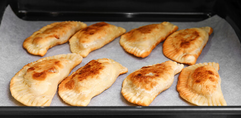 Baking sheet with tasty meat empanadas in oven, closeup