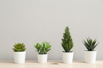 Artificial plants on table near light wall