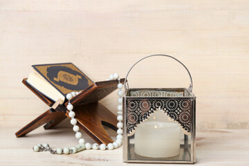 Muslim lamp with burning candle, Koran and prayer beads on light wooden background