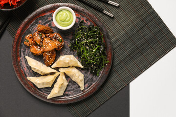 Plate with tasty Chinese dishes on black and white background
