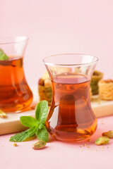 Glass cups of tea with Turkish delight on color background