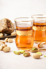 Glasses of Turkish tea and pistachios on white background