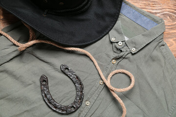 Cowboy hat, shirt and horseshoe on wooden background