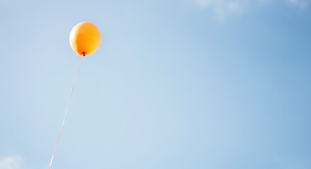 Obraz premium Single orange balloon floating in clear blue sky