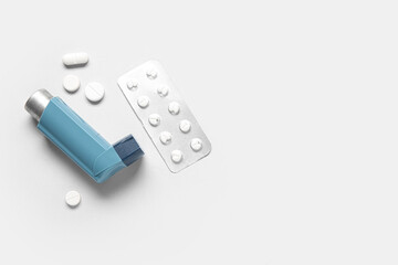 Asthma inhaler and pills on grey background