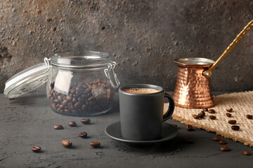 Cup of delicious espresso, coffee beans and jezve on table