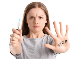 Young female junkie with syringe and word STOP written on her palm against white background