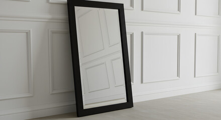 Modern Black Framed Floor Mirror Leaning Against White Paneled Wall